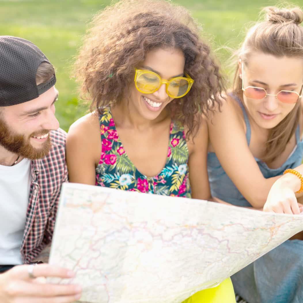 three people having fun looking at a map
